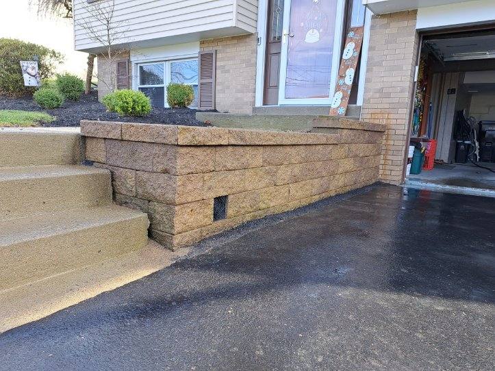 Small retaining wall along driveway with integrated concrete step transition
