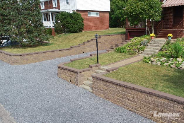Large residential tiered retaining wall system with integrated steps and gravel driveway