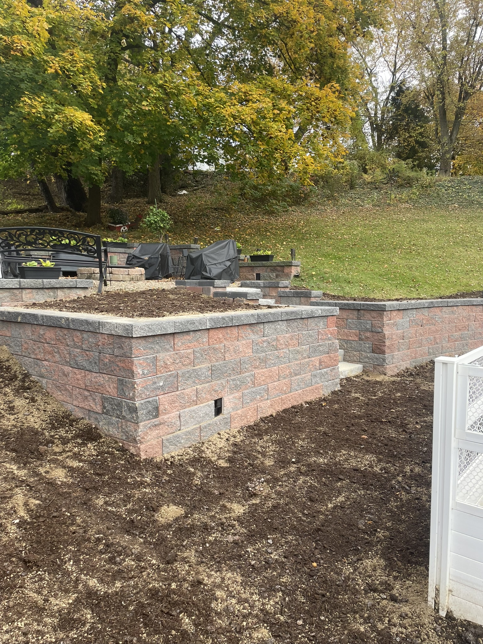 Tiered retaining wall system with large block construction and upper patio area