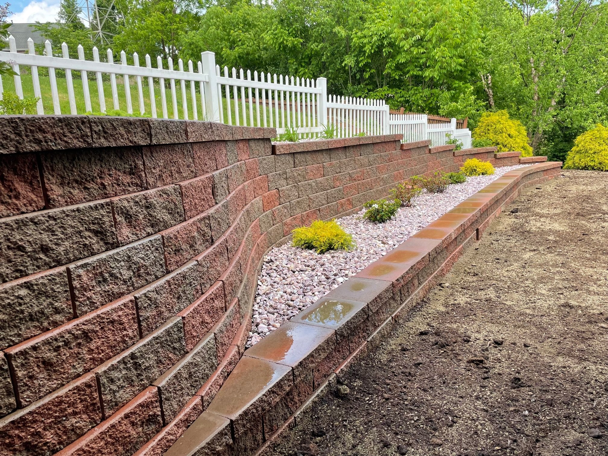 Curved retaining wall with decorative rock bed and integrated landscaping