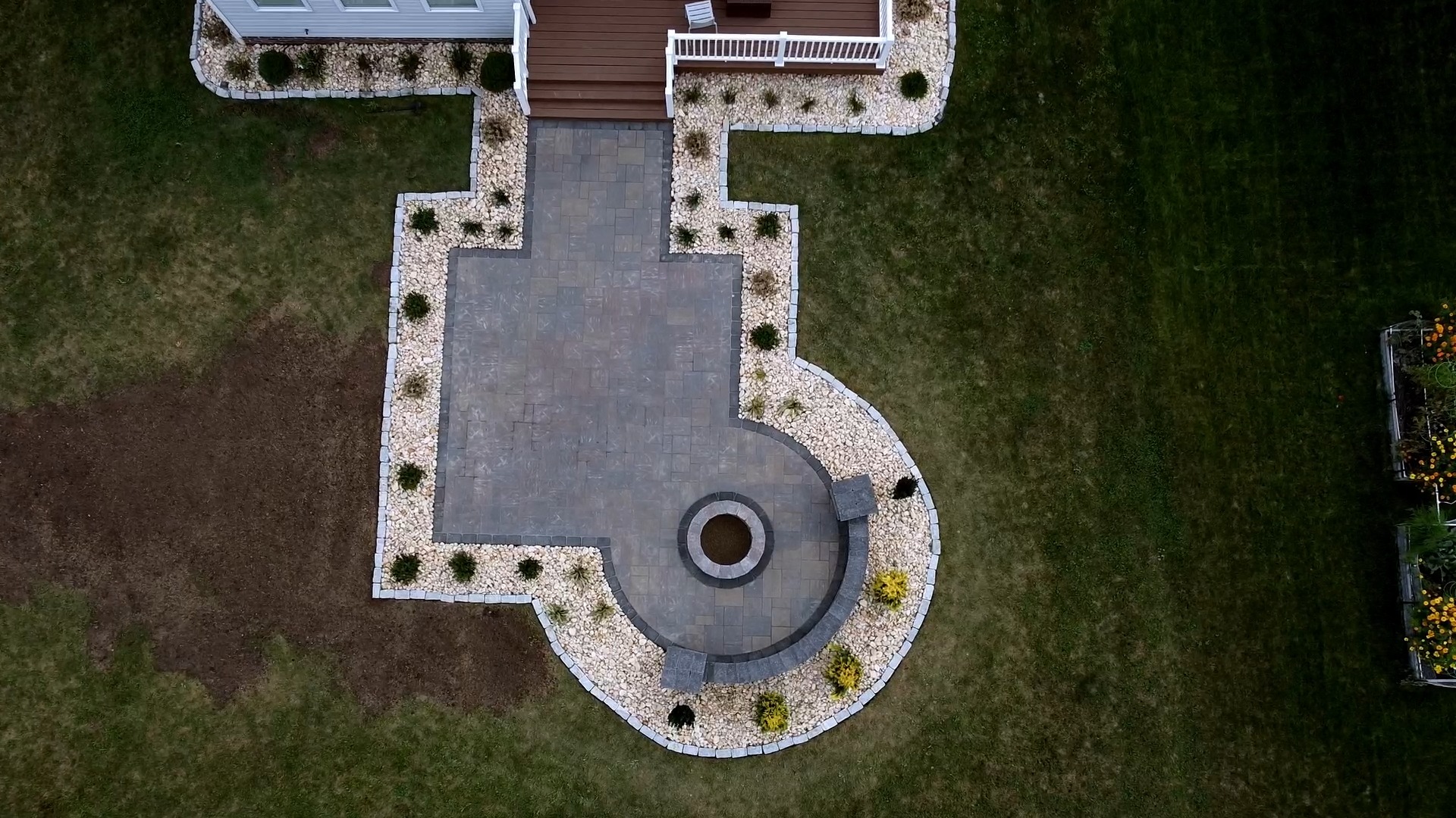 Aerial drone shot of large custom patio with circular fire pit and decorative stone borders