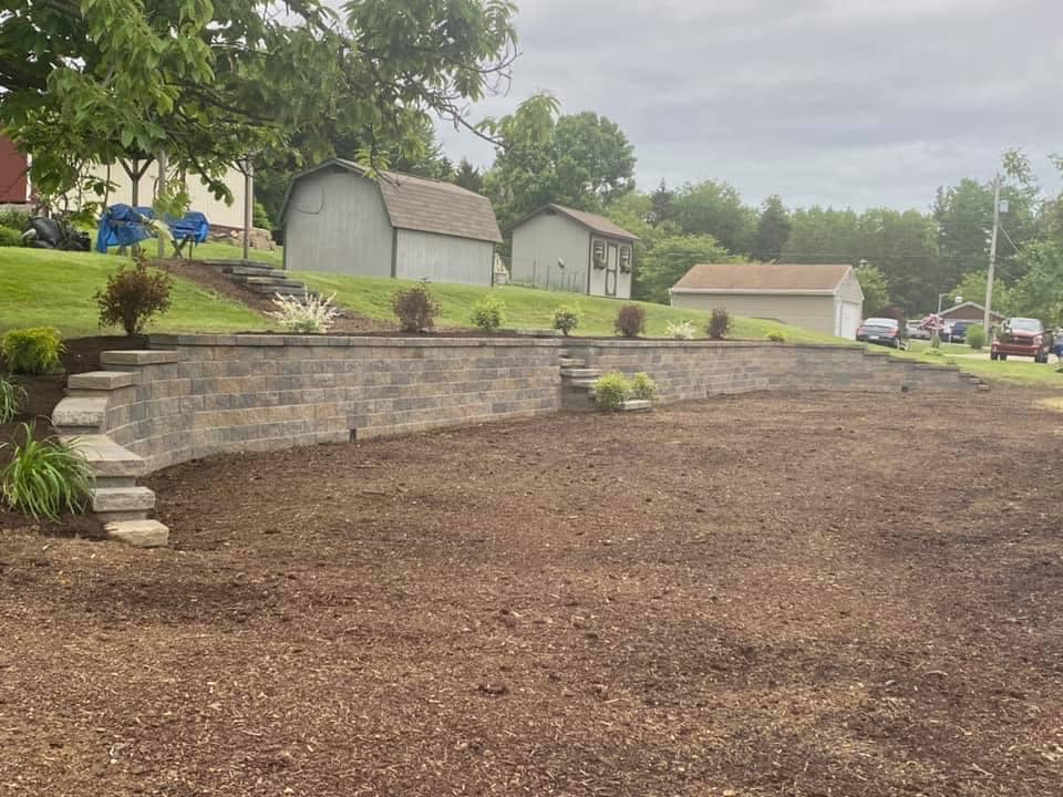 Long retaining wall installation with freshly prepared soil bed ready for landscaping